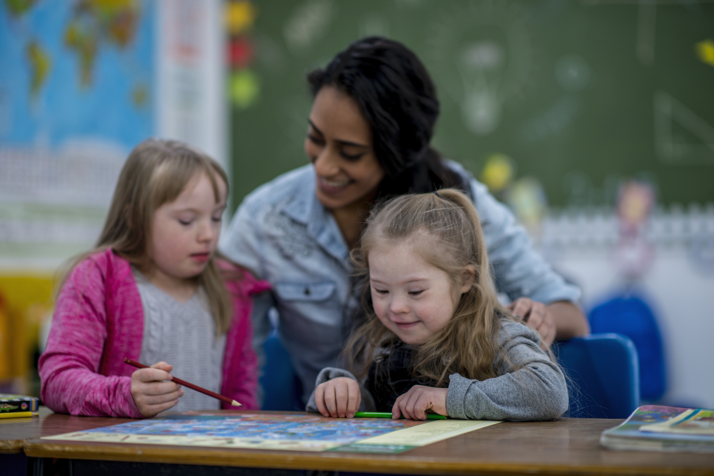 woman teacher helping two students with drawing